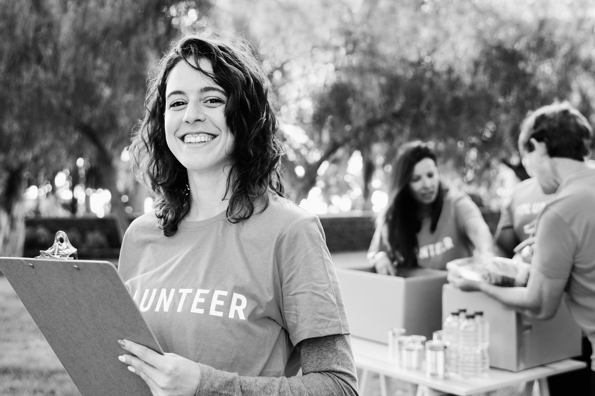 Volunteer working with group of people for food collection community service at City Park - B&W edit